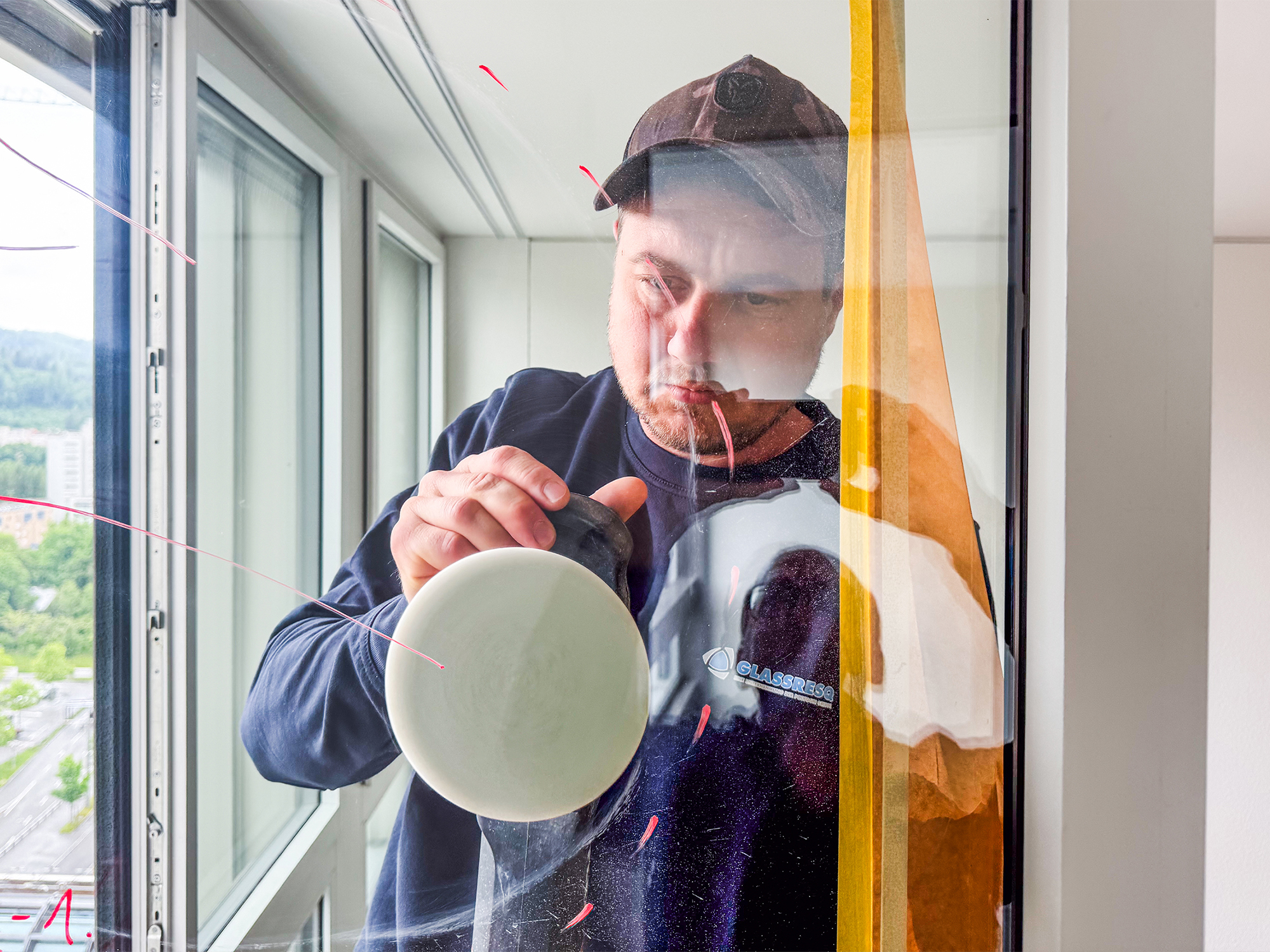 GLASSRESQ Mitarbeiter saniert zerkratztes Glas auf einer Baustelle und entfernt Kratzer aus einer grossen Fensterfront mit mobilem Poliersystem