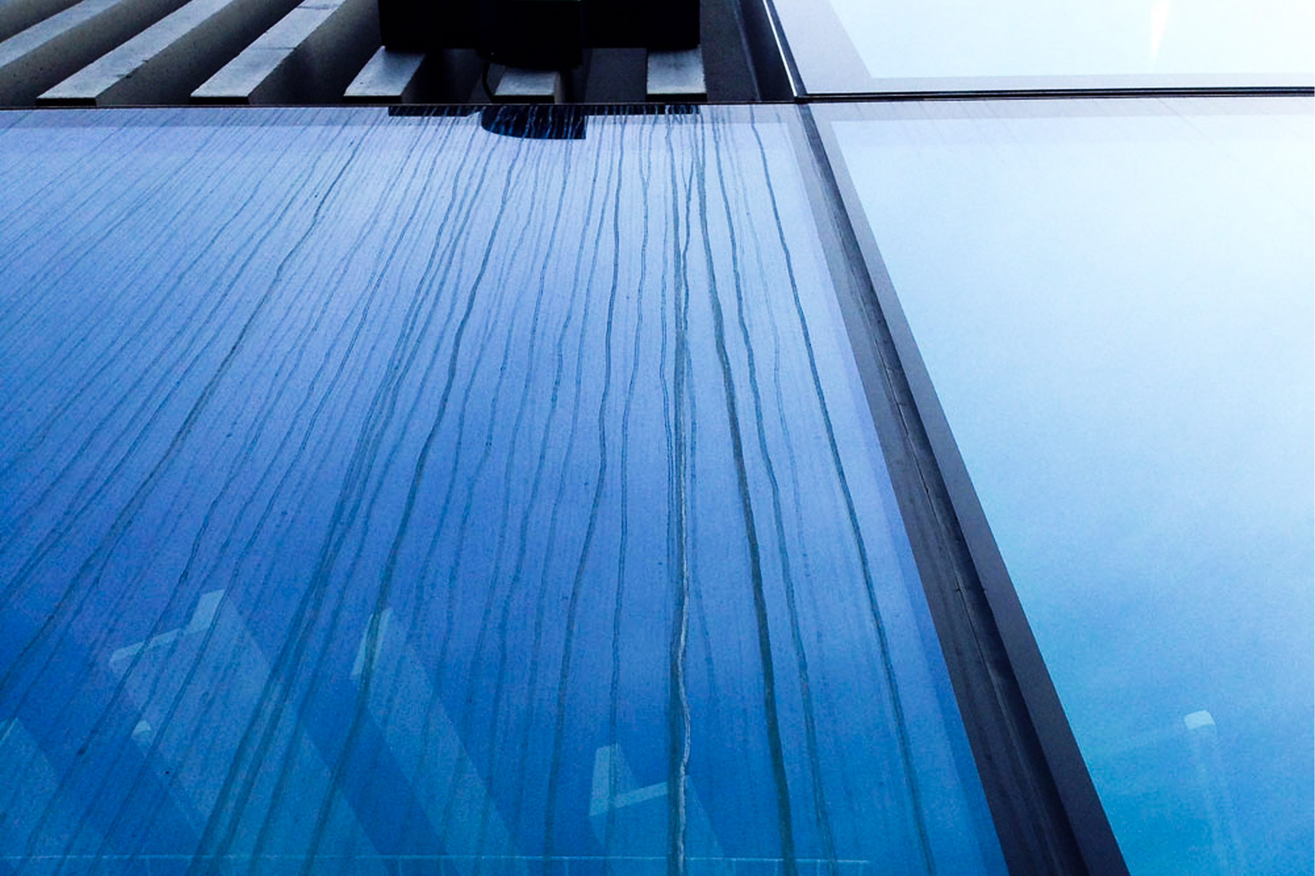 Glaskorrosion durch Zementschleier auf einer Glasfassade – GLASSRESQ Glasfassade mit sichtbaren Verätzungs- und Glaskorrosionsspuren durch Zementschleier nach Bauarbeiten.